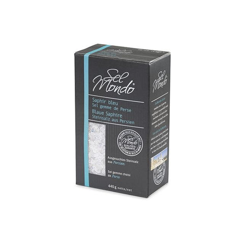 Eine Schrägansicht einer schwarzen „Sel Mondo“-Kartonverpackung für „Saphir bleu“ Steinsalz aus Persien, mit einem hellblauen vertikalen Streifen, einer Gewichtsangabe von 440 g und einem Sichtfenster mit groben weißen und blauen Salzkristallen.