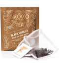 Ein goldfarbenes Tee-Sachet für Sirocco „Black Vanilla“ Schwarztee mit Vanille, neben einem transparenten Pyramidenteebeutel, der mit dunklen, losen Teeblättern gefüllt ist.