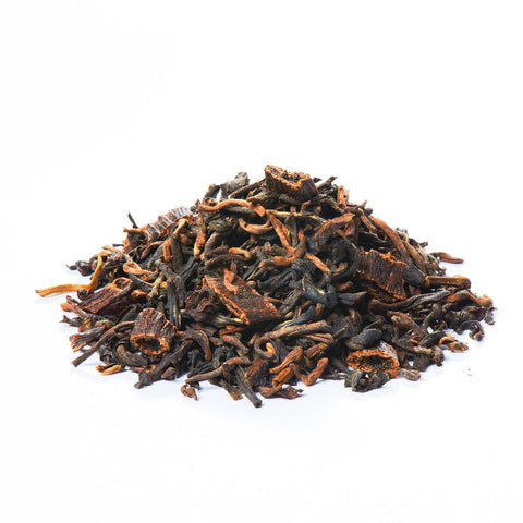 Ein kleiner Haufen loser Sirocco „Black Vanilla“-Tee auf weißem Hintergrund, bestehend aus dunklen, gekräuselten Teeblättern gemischt mit groben, holzigen Vanillestücken.