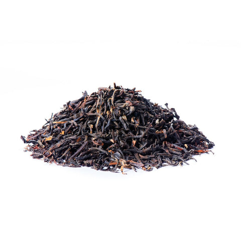 Ein kleiner Haufen loser Sirocco „Golden Assam“-Schwarztee auf weißem Hintergrund, bestehend aus feinen, dunklen fermentierten Teeblättern mit deutlich sichtbaren goldbraunen Blattspitzen.