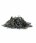 Ein kleiner Haufen loser, dunkelgrüner Teeblätter der Sorte Japanese Sencha auf rein weißem Hintergrund.