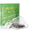 Ein hellgrünes Tee-Sachet für Sirocco „Jasmine Dragon Pearls“ neben einem transparenten Pyramidenteebeutel, der fest gerollte, perlenförmige Grünteeblätter mit Jasminduft enthält.