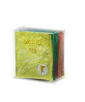 Eine durchsichtige, würfelförmige Box mit der Sirocco Green Tea Selection, die verschiedene Farben von Teebeutel-Verpackungen enthält, wobei die hellgrüne Packung für Japanese Sencha Green Tea im Vordergrund steht.