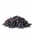 Ein kleiner Haufen loser Sirocco „Purple Breeze“ Darjeeling-Tee auf weißem Hintergrund, bestehend aus dunklen, gekräuselten und leicht gedrehten hochwertigen Schwarzteeblättern.
