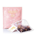 Ein rosa Tee-Sachet für Sirocco „Red Kiss“ Früchtetee neben einem transparenten Pyramidenteebeutel, der mit einer bunten Mischung aus getrocknetem Hibiskus, Hagebutten und Fruchtstücken gefüllt ist.
