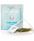 Ein blass minzgrünes Tee-Sachet für Sirocco „Wellness Tea Pure Power“ neben einem transparenten Pyramidenteebeutel, der mit einer leuchtend grünen Kräuter- und Grünteemischung gefüllt ist.