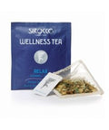 Ein dunkelblaues Tee-Sachet für Sirocco „Wellness Tea Relax“ neben einem transparenten Pyramidenteebeutel, der mit einer beruhigenden Kräuterteemischung aus Melisse und Lavendel gefüllt ist.