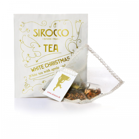 Ein weißes Tee-Sachet für Sirocco „White Christmas“ Tee mit goldenen festlichen Sternmustern und einem transparenten Pyramidenteebeutel, gefüllt mit weißem Tee, Apfelstücken und Gewürzen.