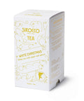 Eine weiße Kartonverpackung für Sirocco „White Christmas“ Bio-Weißtee, verziert mit goldenen festlichen Sternen und Ornamenten, sowie einer Seitenwand mit mehrsprachiger Zutatenliste.