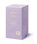 Eine lavendelfarbene Kartonverpackung für Sirocco „White Silver Needle“ Bio-Weißtee mit Jasmin, verziert mit eleganten weißen Ornamenten und einer Seitenwand mit der mehrsprachigen Zutatenliste.