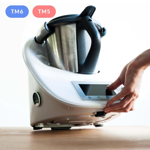 Hand justiert die Basis eines weißen Thermomix Geräts mit TM6 und TM5 Abzeichen.
