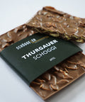 Schoggistängel mit Nüssen und einer dunkelgrünen Banderole mit der Aufschrift „Thurgauer Schoggi“.