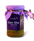 Glas mit Thai Orchid Selection Tom Kha Suppen Paste (100% vegetarisch, 115 g), verziert mit lila Stoff und einem Orchideen-Anhänger.