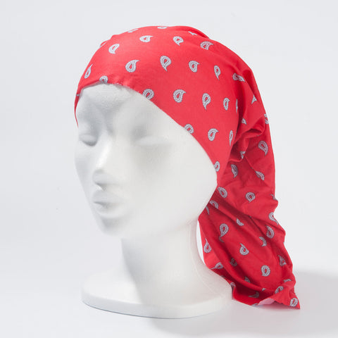 Ein rotes Multifunktionstuch mit weißem Paisley-Muster, das als „Saharatuch“ auf einem weißen Modellkopf getragen wird und hinten lang herabfällt.