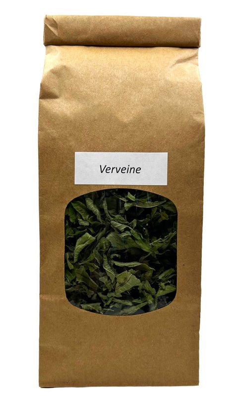 Eine braune Papiertüte mit einem kleinen Sichtfenster, das getrocknete, lange grüne Eisenkrautblätter zeigt, beschriftet mit einem weißen Etikett „Verveine“