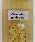Eine braune Papiertüte mit einem kleinen Sichtfenster, durch das getrocknete, grobe Zwiebelstücke zu sehen sind, beschriftet mit einem weißen Etikett „Zwiebeln gekippelt“.